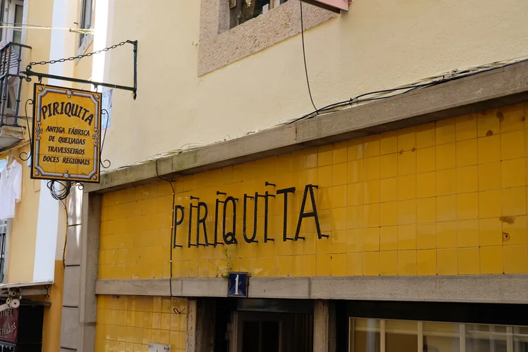 The Piriquita pastry shop on Rua das Padarias, with its name in black letters on yellow tiles, door number 1 and a hanging tiled sign.
