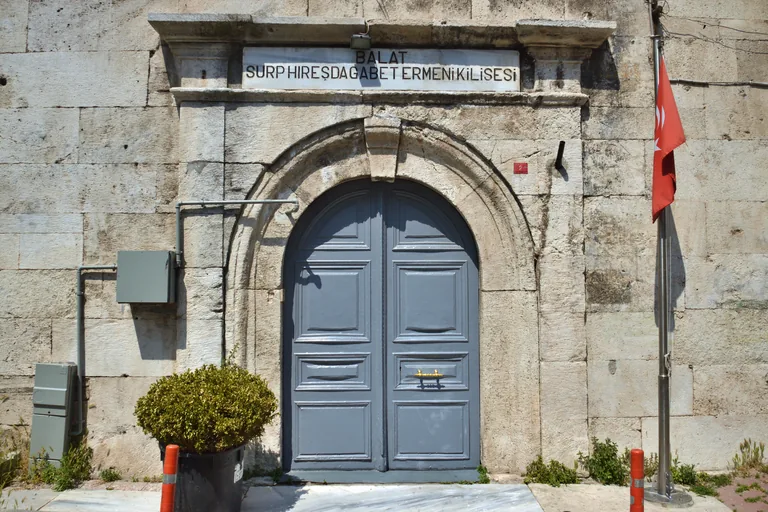 The stone doorway of Surp Hreshdagabet Armenian Church, with grey double doors beneath its name plaque.
