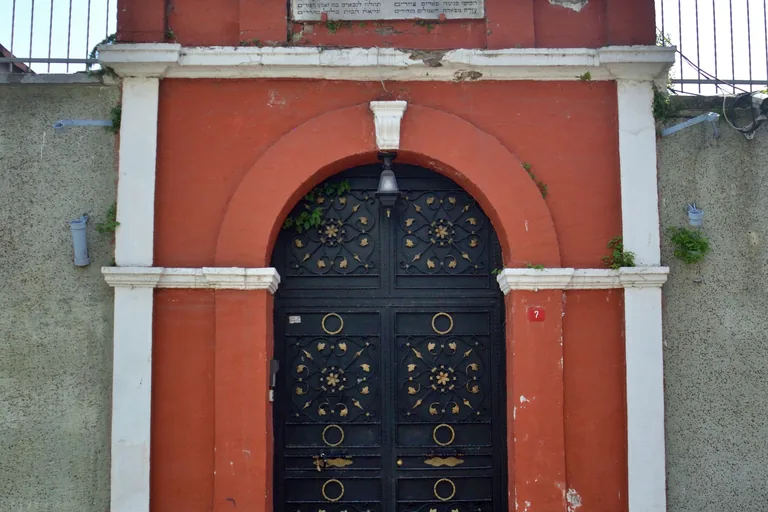 The arched gateway of Ahrida Synagogue, with black studded doors set in a red wall.