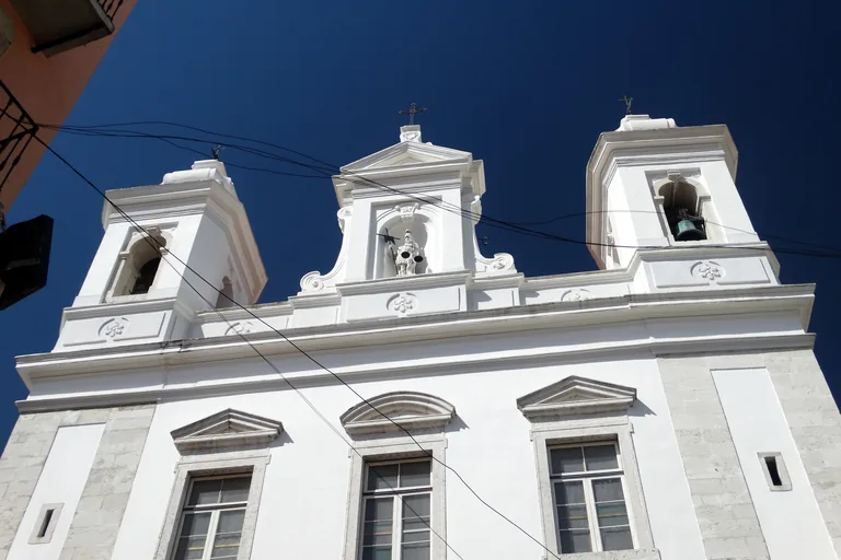 The white bell towers of the Church of São Miguel seen from below.