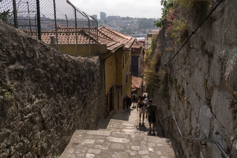 A stepped lane in the Barredo running down between stone walls towards the rooftops and the river.