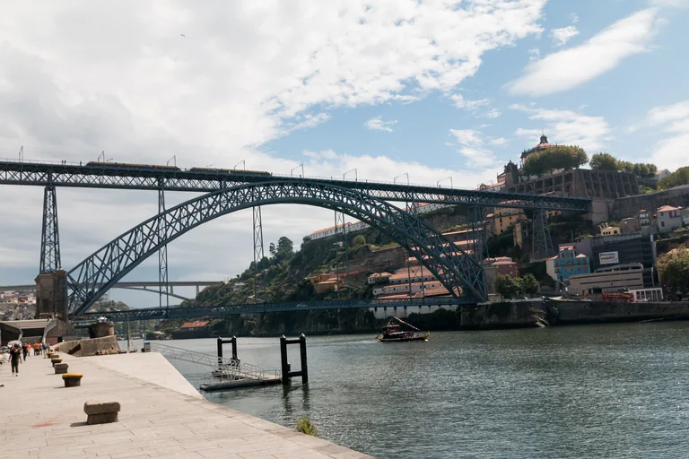 The iron arch of the Dom Luís I Bridge over the Douro, seen from the quay on the Porto bank.