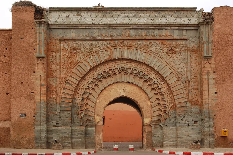 The carved stone face of Bab Agnaou, with bands of carved inscription and layered arches around a single archway set into the ochre kasbah wall.