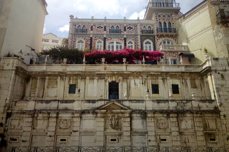 The stone front of the Chafariz d'El-Rei below a tiled palace.