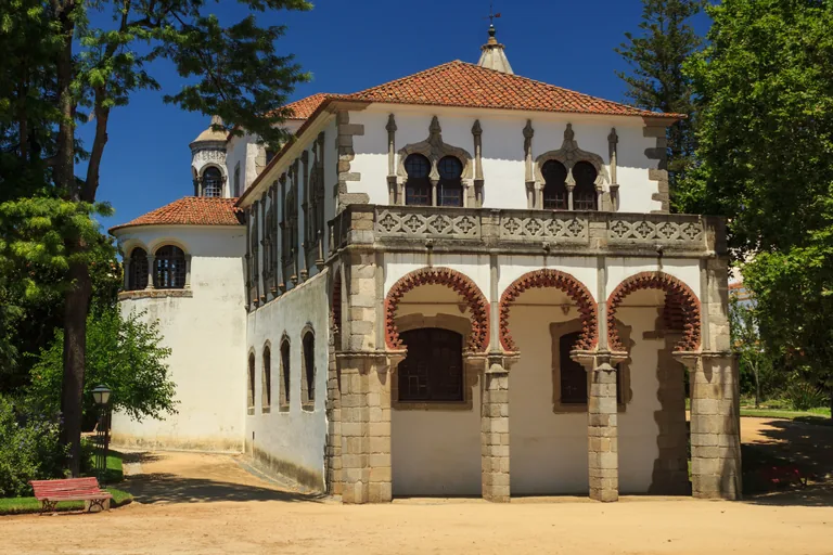 The white gallery of the Palace of King Manuel in the public garden, with three brick edged arches below paired windows and a round corner turret.