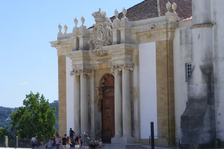 The carved stone doorway of the Joanina Library, crowned by the royal arms, at a corner of the university courtyard.