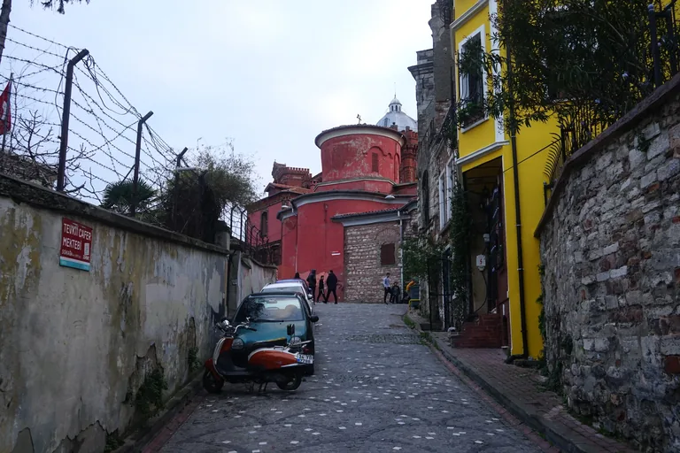 The red walls and dome of St Mary of the Mongols at the top of a cobbled lane.