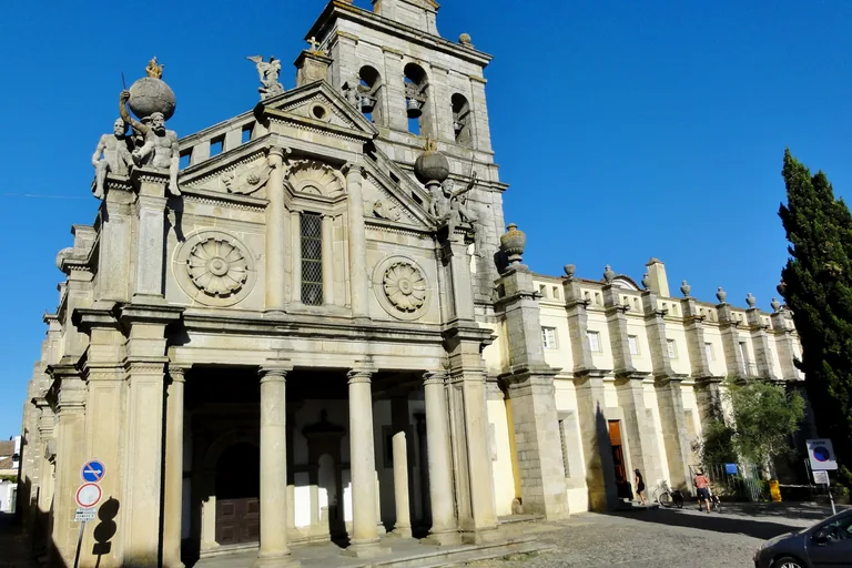 The classical front of the Church of Our Lady of Grace, with a columned porch, two stone roundels and seated stone giants at its upper corners.