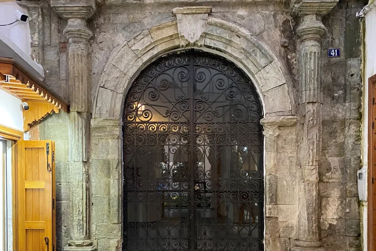 The stone portal of Dar Niaba, with fluted columns either side of a round arch closed by a wrought iron gate, and the house number 41 on the wall.
