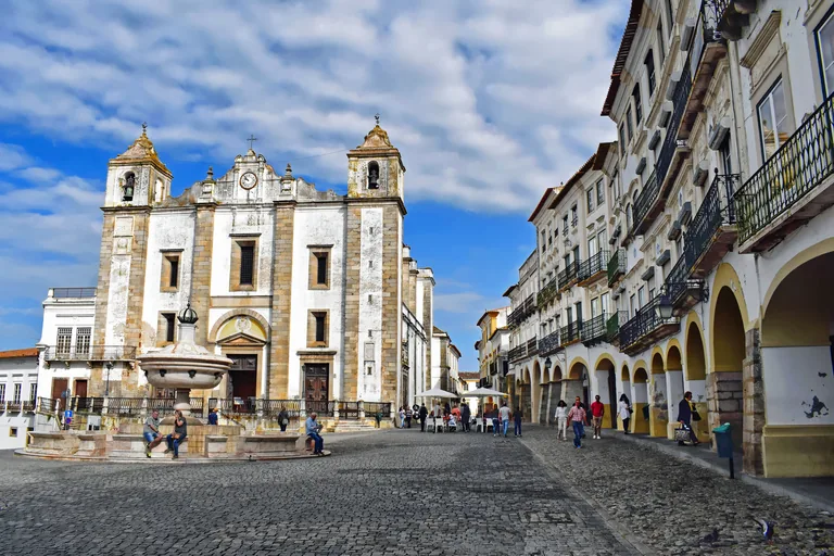 The Praça do Giraldo seen from its south side, with the marble fountain, the twin towered front of Santo Antão and arcaded houses on the right.