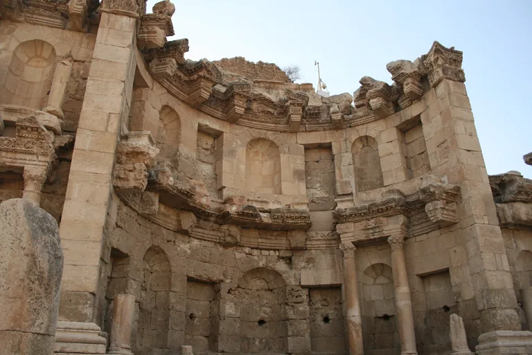 The Nymphaeum at Jerash, a two storey curved stone facade with arched and square niches, carved cornices and slender columns on the lower level.