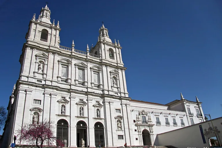 The white twin towered front of São Vicente de Fora against a blue sky.