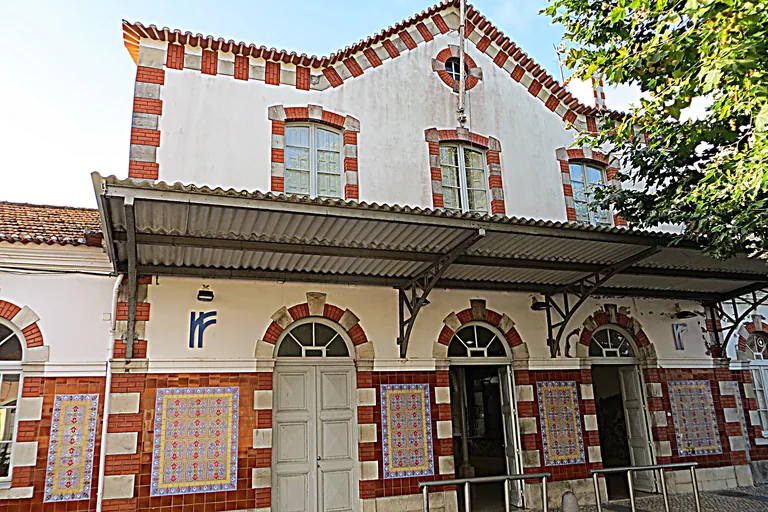 The front of Sintra Station, with red and white brick trim, tile panels between round arched doorways and a metal canopy over the entrance.