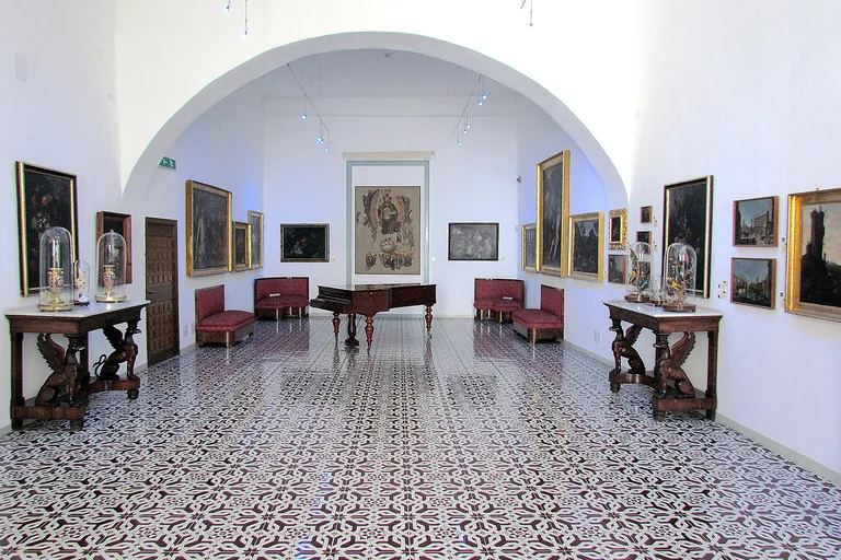 A bright gallery lined with paintings inside Cefalu's Mandralisca Museum.
