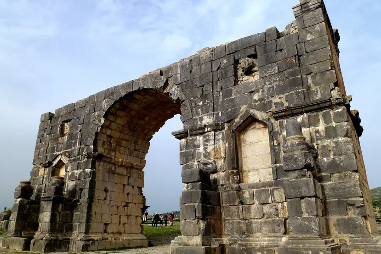 The dark-stone Arch of Caracalla at Volubilis.