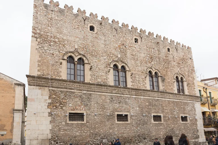 The crenellated stone facade of Palazzo Corvaja in Taormina.