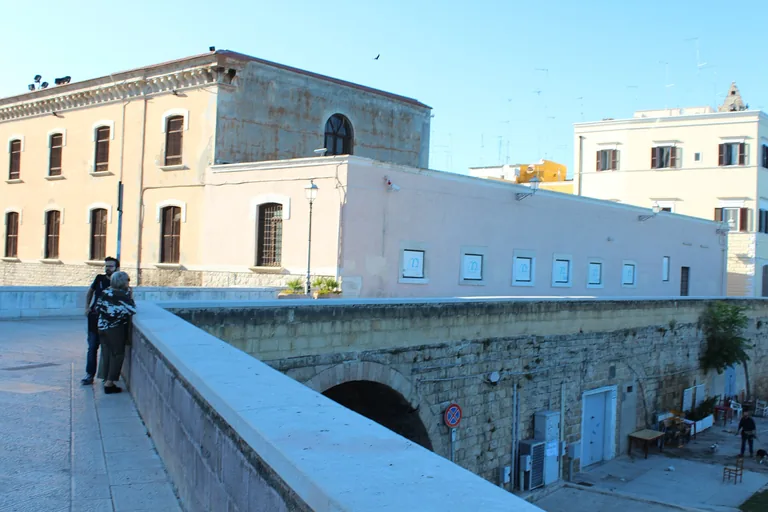 Bari's raised stone sea-wall walkway beside old-town buildings.