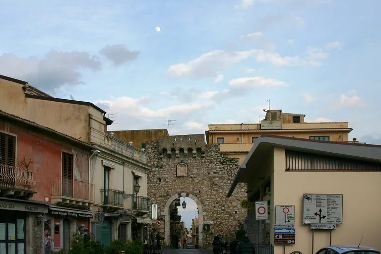 The stone arch of Porta Catania opening onto a Taormina street.
