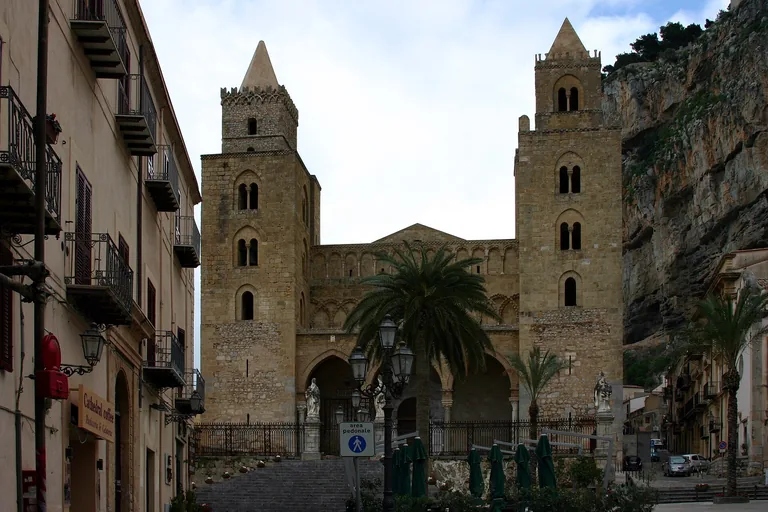 Cefalu Cathedral's twin towers at the end of a narrow old-town street.