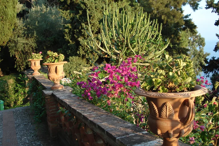 Flowering planters and cacti along a path in Taormina's Villa Comunale.