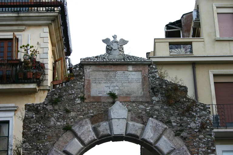 The upper stone arch and crest of Porta Messina in Taormina.