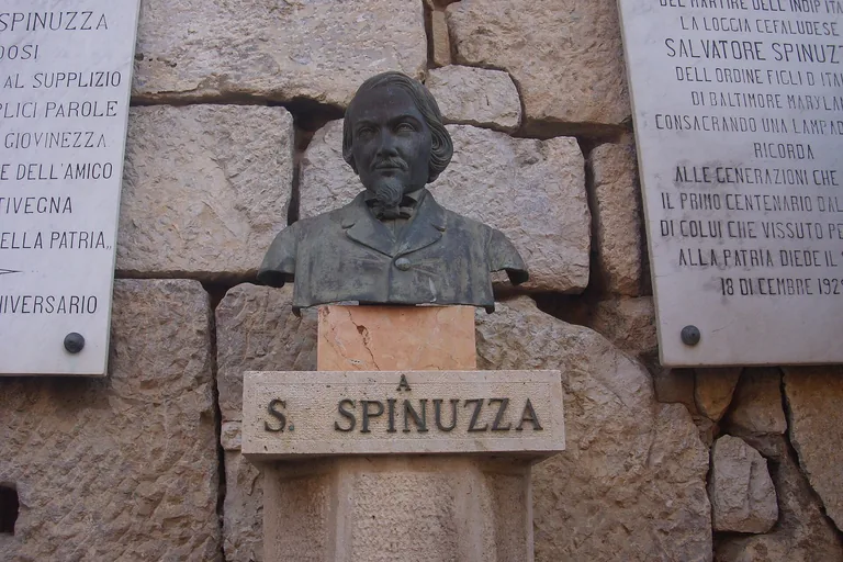 The bronze memorial bust of Salvatore Spinuzza mounted on a stone wall in Cefalu.