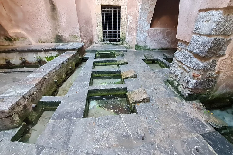 Stone washing basins and water channels inside Cefalu's medieval wash-house.