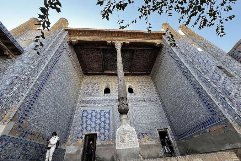 The harem courtyard of Tash Hauli — blue majolica walls and a carved column under the painted ayvan