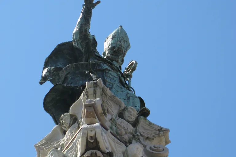 Bronze statue of Sant'Oronzo atop its column against a blue sky.