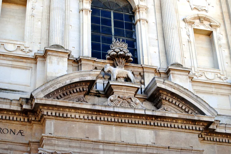 Carved crown, palm, and animal motifs on the facade of Chiesa di Sant'Irene.
