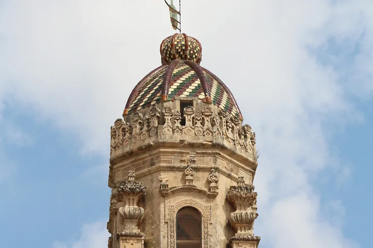Majolica-tiled crown of Lecce Cathedral's bell tower above Piazza del Duomo.
